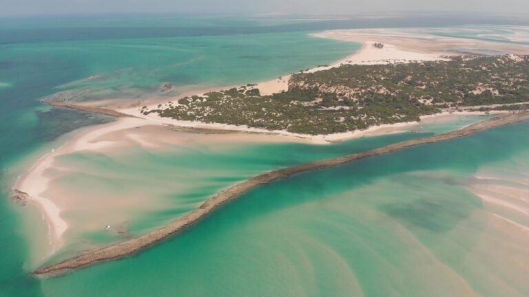 Turista a caminhar com seguranca numa praia tropical em Mocambique